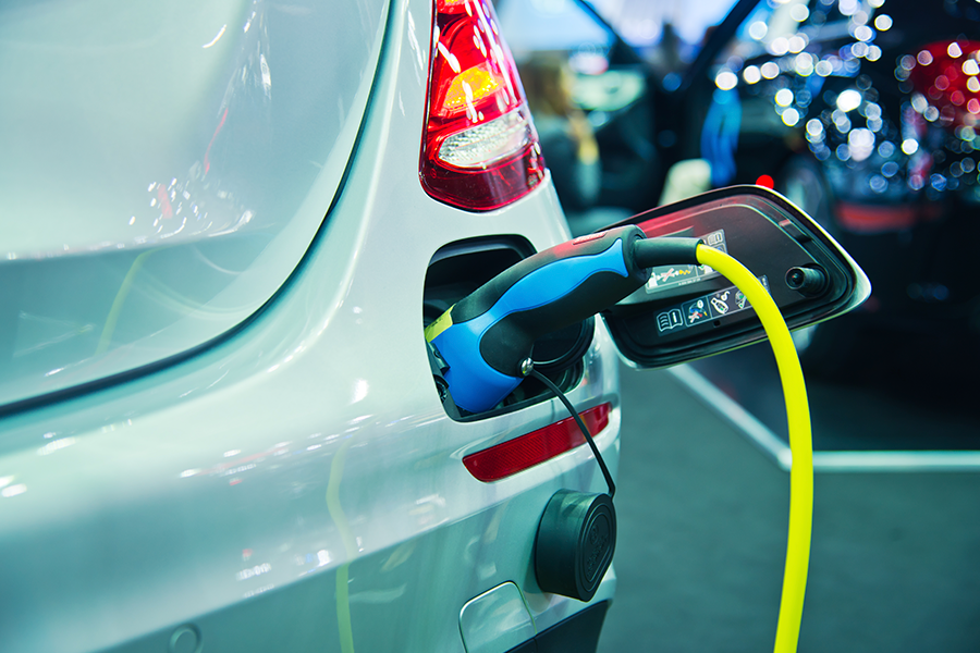 Primer plano de la parte trasera de un vehículo eléctrico plateado que está enchufando, cargándose.