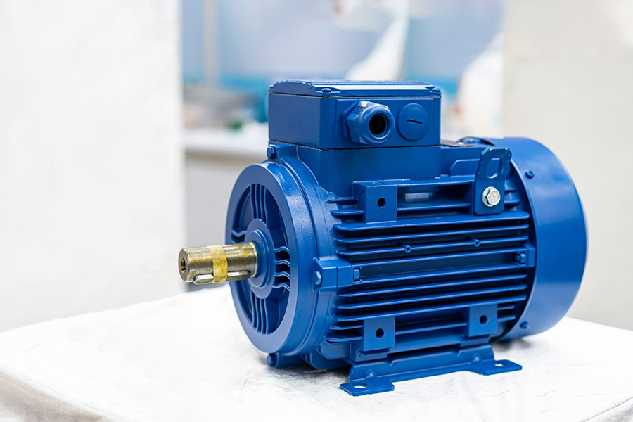 Primer plano de un motor eléctrico industrial azul sobre una superficie blanca en un entorno interior luminoso.