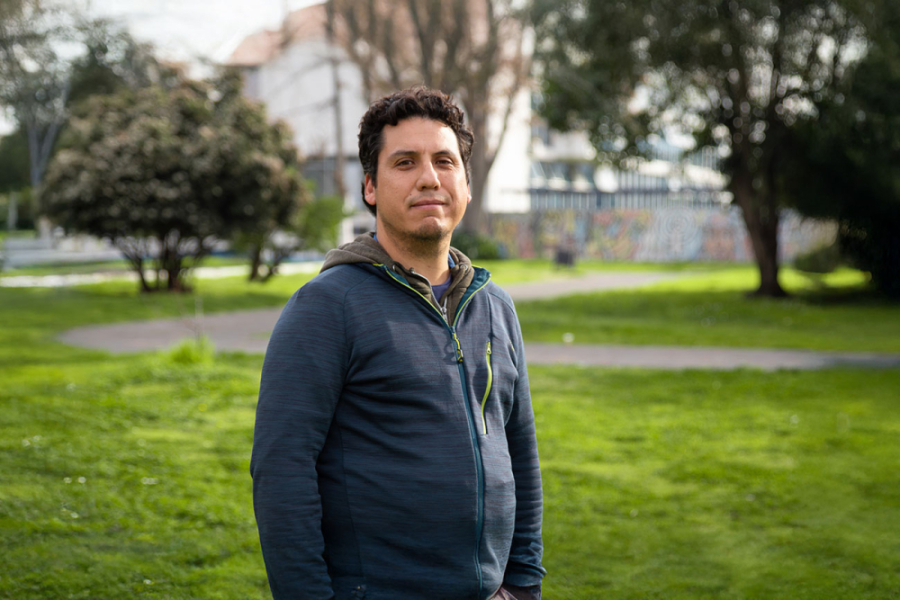 En la fotografía aparece el Dr. Daniel Aravena, académico del Departamento de Química de los Materiales. Está en los pastos a un costado del edificio de Radio y TV Usach. De fondo se puede observar el edificio de Rectoría.