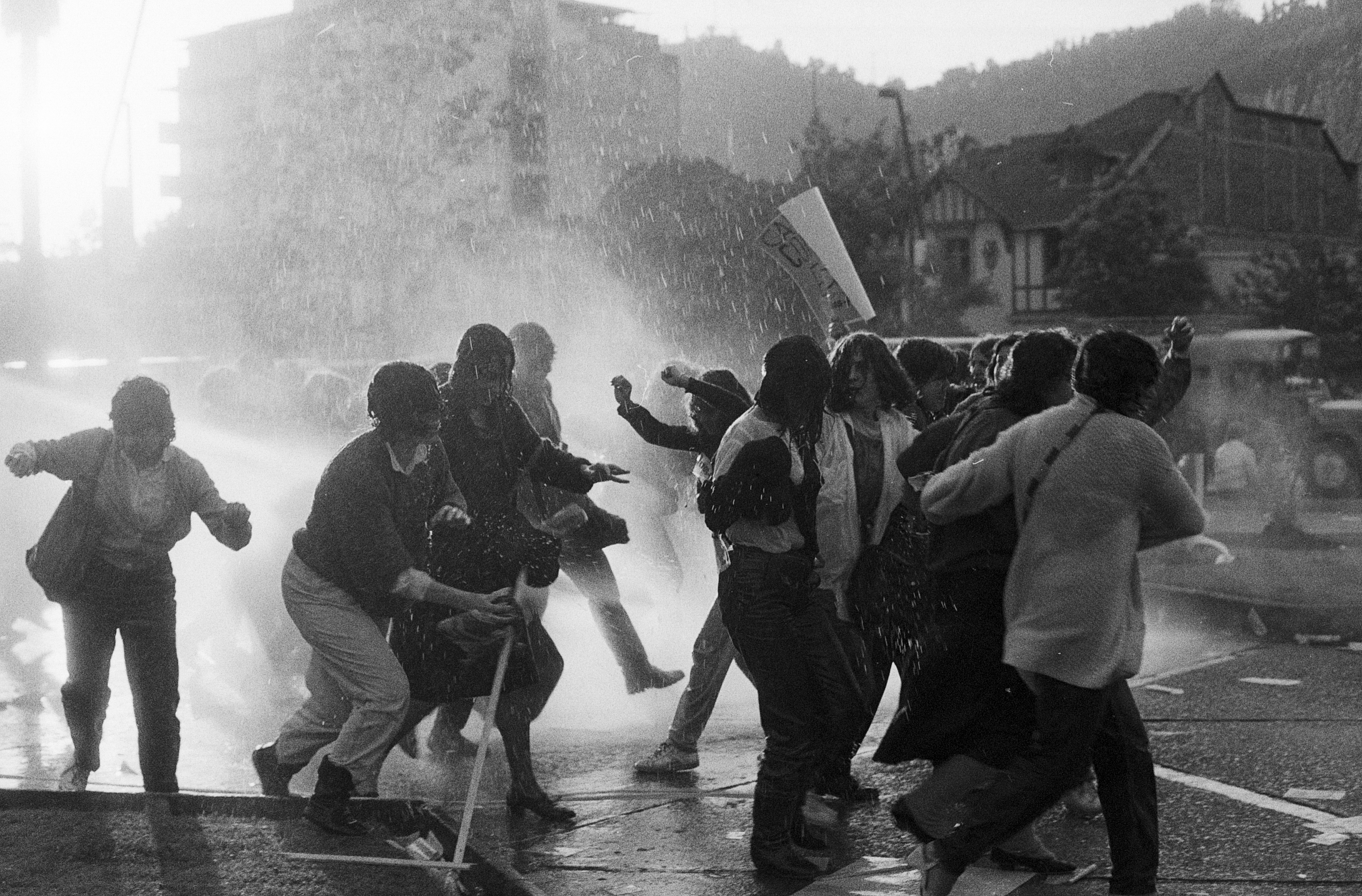 Imagen referente a la actividad, donde se ve un grupo de personas protestando en los años de la universidad técnica del estado, las cuales están siendo dispersas