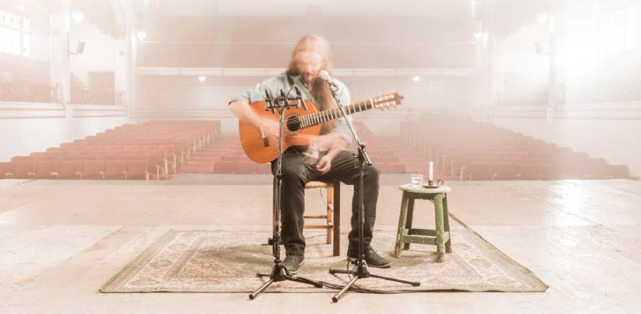 Imagen referente a la actividad, donde ve una persona en el escenario con su guitarra y el micrófono.