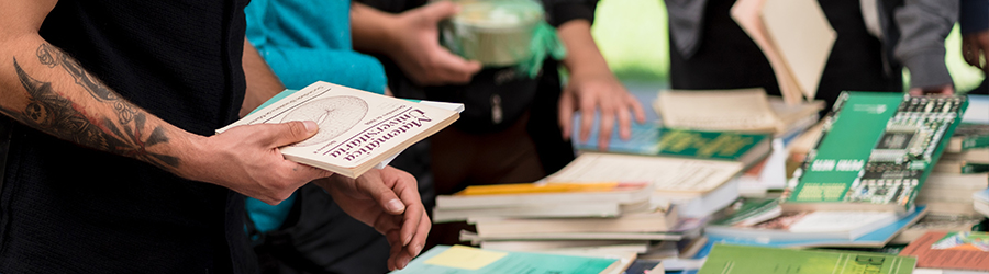 En la foto se ve a un estudiante sosteniendo un libro de Matemática universitaria, y debajo aparece una mesa con más ejemplares de libros.