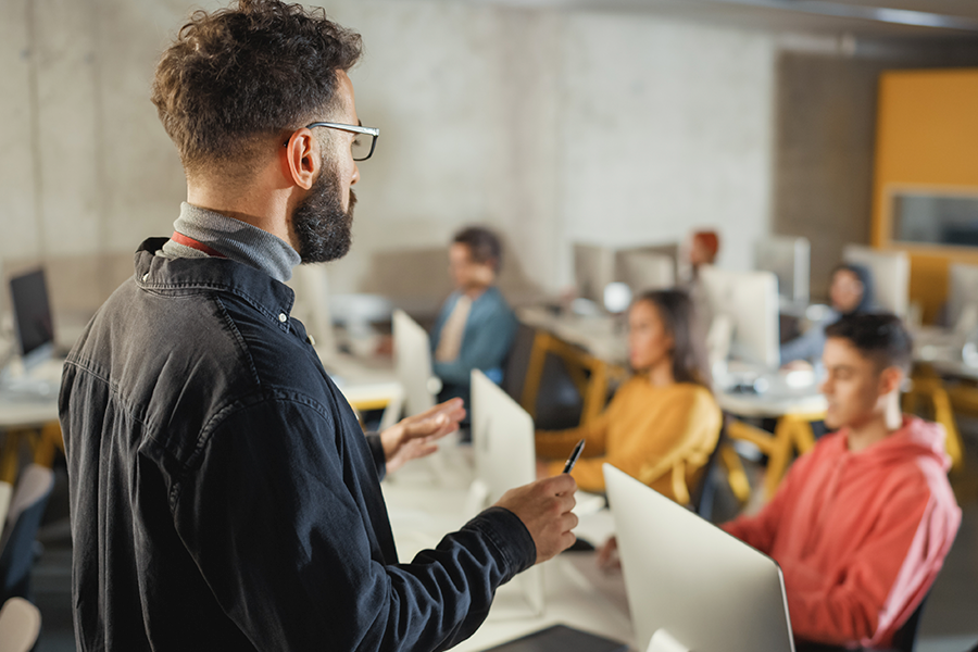 Photograph of a young professor in front of a class of university students.