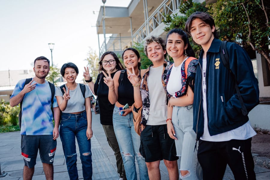 En la fotografía aparecen estudiantes saludables de la Universidad e Santiago de Chile, saludando a la cámara en el antiguo edificio de la FAE.