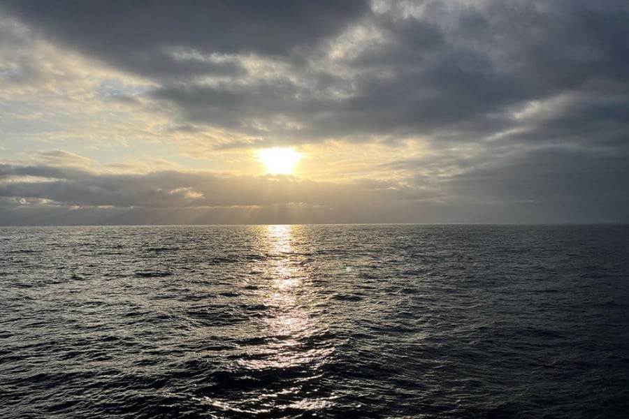 La foto muestra el horizonte, con una puesta de sol en el mar