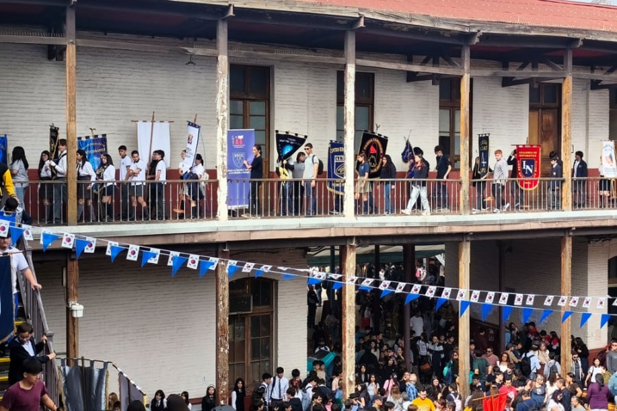 En la imagen aparecen niños de los colegios participantes del CMAT 2026, por entre los corredores de la Escuela de artes y Oficios., tanto en primer como en segundo piso. La fotografía muestra los estandartes de cada establecimiento y los estudiantes portándolos.