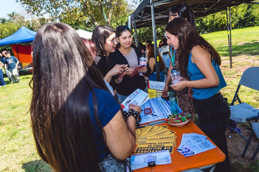 En la imagen aparece estudiantes en un stand de la feria solicitando información