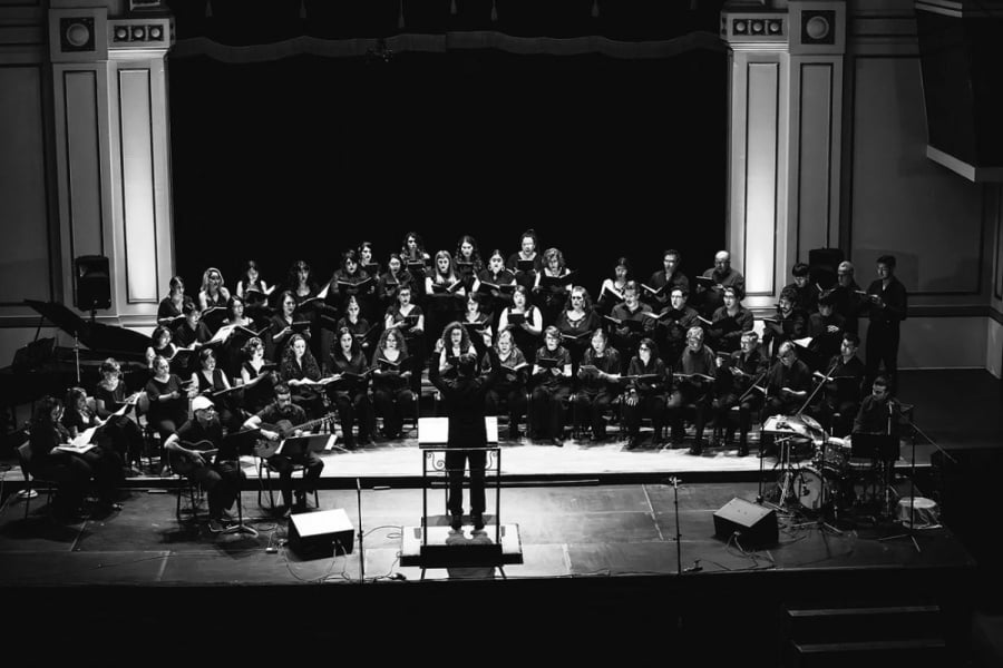 La imagen muestra al coro en el Aula Magna de la universidad