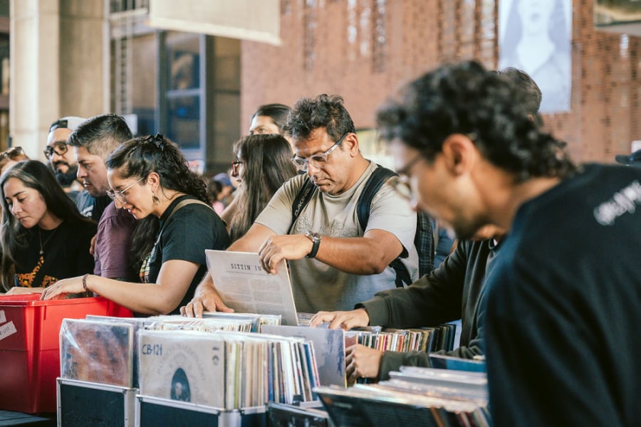 En la imagen se muestran a personas revisando vinilos en la feria en el GAM