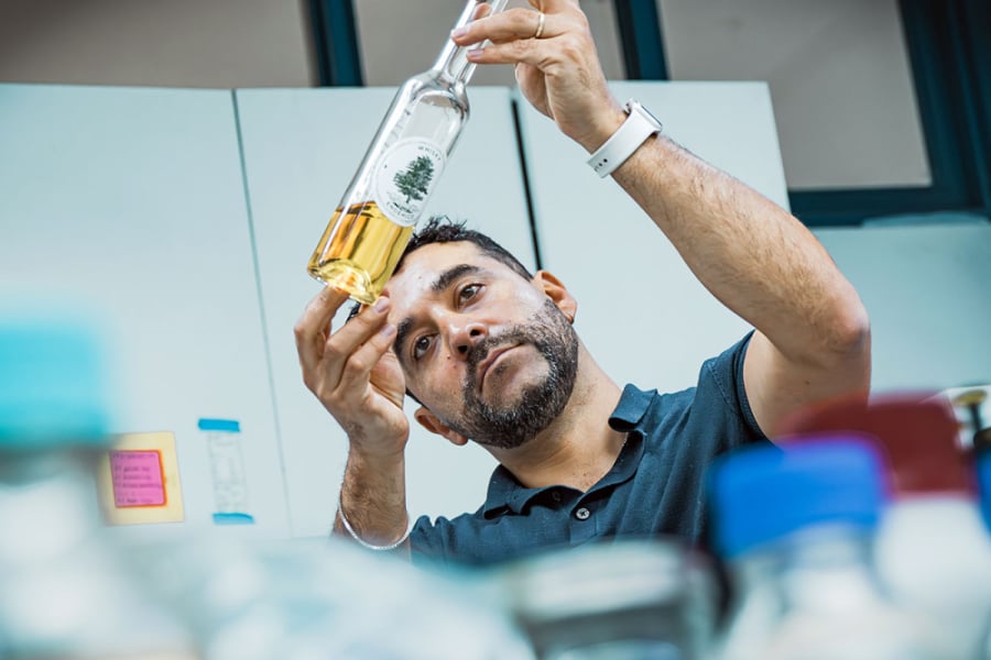 la imagen muestra al investigador manipulando una botella con cerveza en su laboratorio