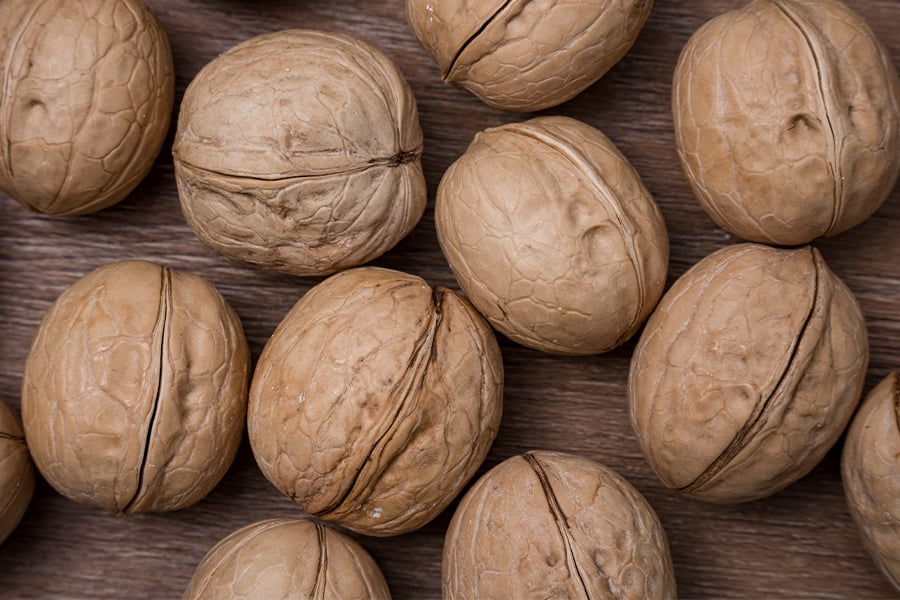 Nueces enteras, sin pelar, con su cáscara, sobre una superficie de madera.