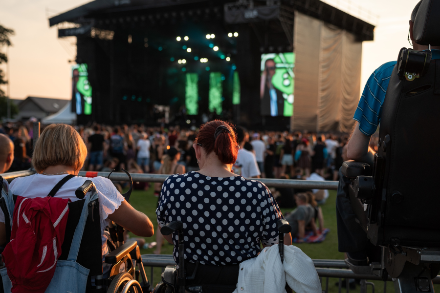 An outdoor concert at sunset with people in wheelchairs in a reserved area.