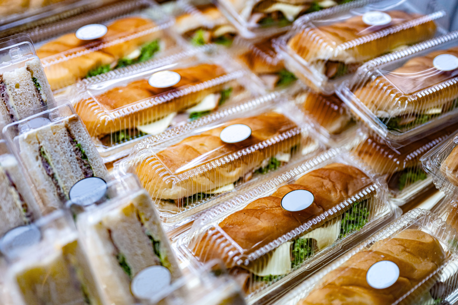 Sandwiches and baguettes packaged in clear plastic containers on display.