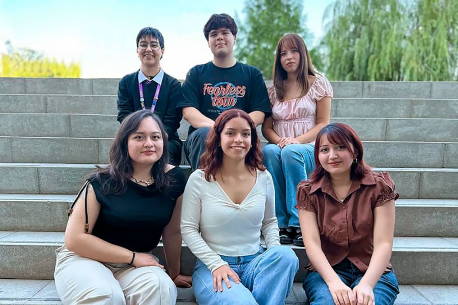 La imagen muestra a las y los estudiantes del proyecto, sentados en las escaleras de la FAE