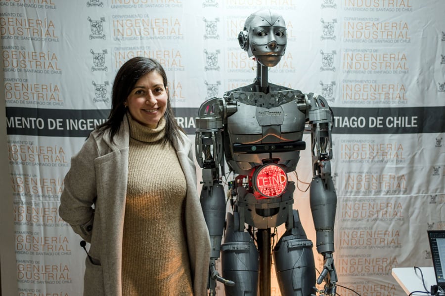 En la imagen aparece la Dra. Lorena delgado junto a ATOM, uno de los robots de la Usach