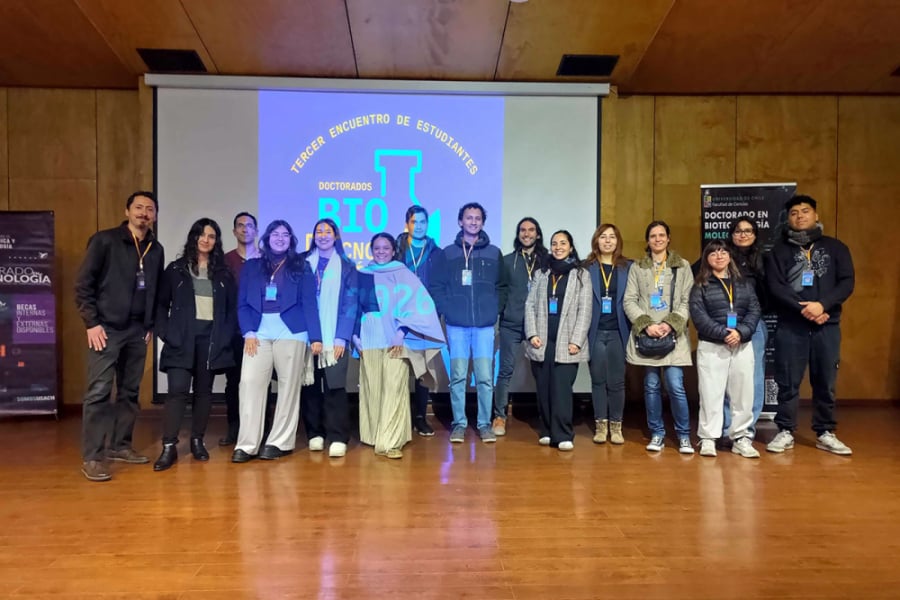 La imagen muestra al docente junto a las y los estudiantes en el escenario del evento